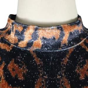 Détail du col montant en velours avec des motifs abstraits orange et noir sur le haut