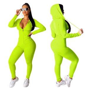 Detail van een neon groene tweedelige sportset met capuchonjack en nauwsluitende broek