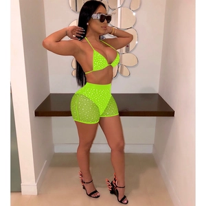 Detail of neon green two-piece set featuring mesh overlay and shimmering sequins