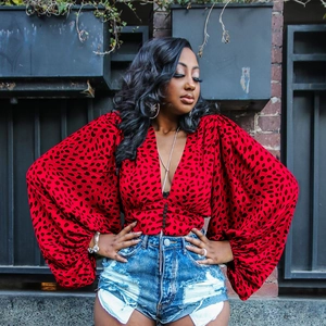 Detail of red leopard print blouse with lantern sleeves and distressed denim shorts