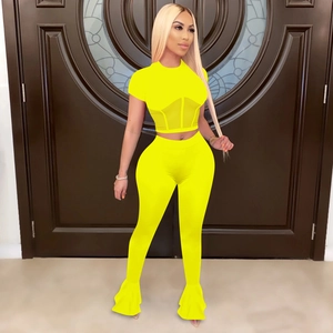 Detail of neon yellow two-piece set featuring mesh waist panels and flared sports trousers