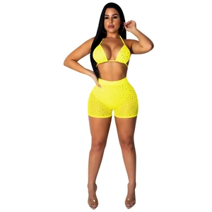 Detail of neon yellow two-piece set with shiny rhinestones on bikini top and high-waist shorts
