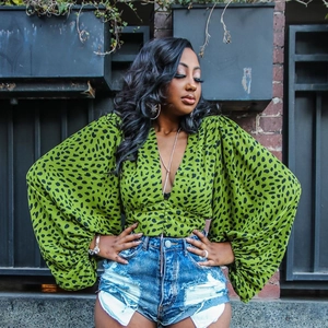 Detail of green leopard print top with deep V-neck, button front and oversized lantern sleeves