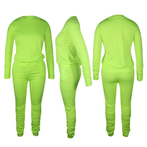 Dettaglio del completo due pezzi verde neon con polsini arricciati e maglia a maniche lunghe