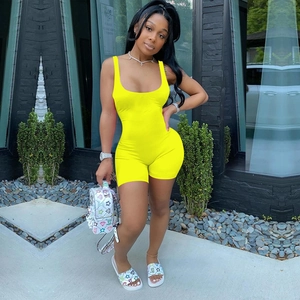 Outdoor shot of a bright yellow slim-fit romper featuring a deep U-neck and sleeveless design