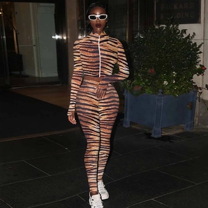 Outdoor street view of a two-piece women's activewear set with bold orange tiger print