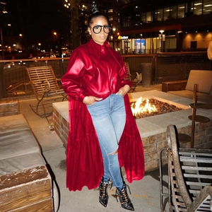 Outdoor night shot of a bright red glossy PU leather long coat with flared hemline