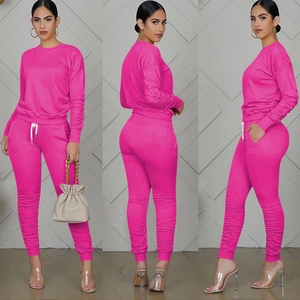 Dettaglio della tuta rosa rossa con polsini a costine e pieghe sui pantaloni sportivi