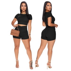 Women's black ribbed two-piece set featuring short sleeve crop top and ruched shorts