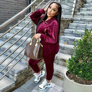 Detailed texture of burgundy velvet tracksuit with high-shine finish and silver zipper detail