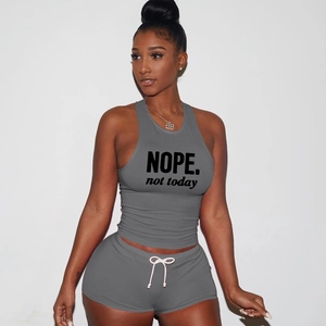 Detail of grey athletic crop top with NOPE print and pink drawstring on shorts