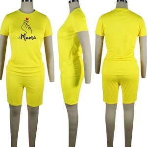 Tre viste di un completo giallo a due pezzi con stampa Mama e design del gesto del cuore