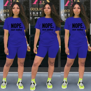 Dettaglio del set sportivo blu con crop top stampato NOPE e pantaloncini da ciclista