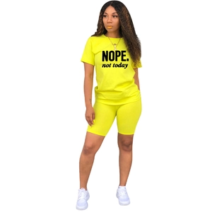 Vista dettagliata del completo a due pezzi verde neon con stampa NOPE nera sulla t-shirt