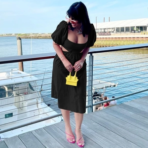 Détail de la robe midi noire à taille découpée avec manches bouffantes et col carré
