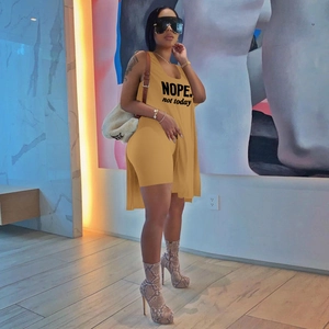 Detail of mustard yellow two-piece set featuring longline vest with NOPE slogan and shorts