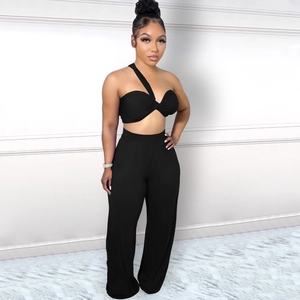 Détail d'un ensemble deux pièces noir avec haut à une épaule et pantalon large à taille haute