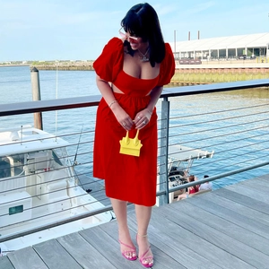 Détail de la robe midi rouge à manches lanternes avec découpe à la taille et col carré