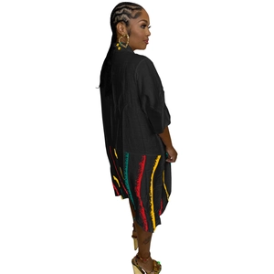 Detailed close-up of colorful striped pattern on the hem of a black shirt dress