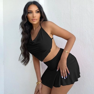 Detail shot of black cowl neck backless top and ruched mini skirt set on a model