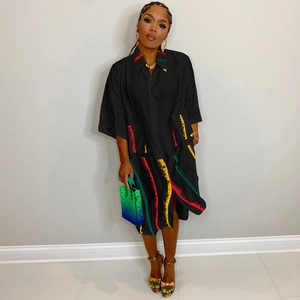 Close-up of black shirt dress featuring colorful abstract stripes and large side pockets