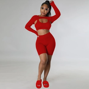 Three-piece red activewear set including long sleeve shrug, sports bra and bike shorts