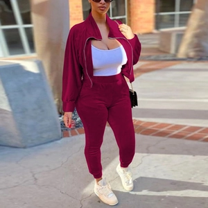 Close-up of burgundy velvet tracksuit featuring silver zipper pockets and elastic cuffs