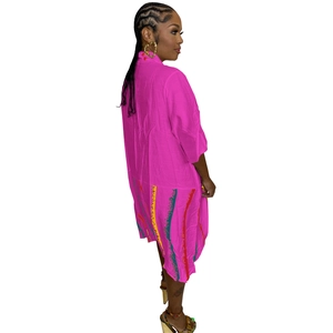 Detail of bright pink oversize maxi dress featuring colorful wavy vertical stripe hem