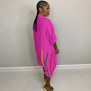 Detail of loose pink shirt dress featuring colorful graffiti vertical stripes at the hem