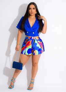 Detail showing bright blue cropped top with double-breasted buttons and colorful printed shorts