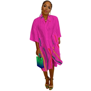 Detail of fuchsia shirt dress featuring colorful vertical print and large pockets