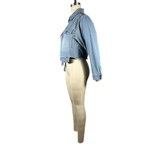 Détail de veste en jean bleu clair avec rivets métalliques et ourlet effiloché naturel