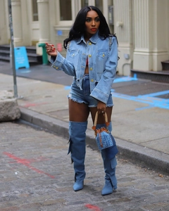 Détail de la veste en jean bleue avec boutons dorés et rivets décoratifs aux épaules