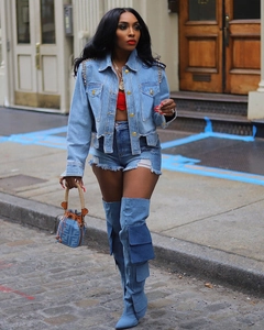 Détail d'une veste en jean bleu clair à clous et de bottes en jean avec poches