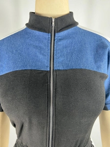 Detail of high neck colorblock jumpsuit featuring blue denim and black fabric with zipper