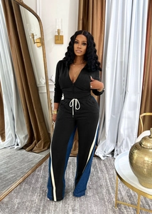 Detail of black tracksuit set showing side stripes on trousers and drawstring waist
