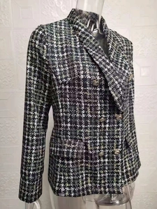 Detailansicht der schwarz-weißen Tweed-Struktur und der geprägten Goldknöpfe am Blazer