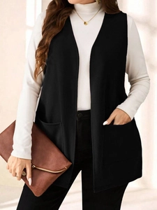 Dettaglio di un gilet lungo nero senza maniche con grandi tasche per un look ufficio chic