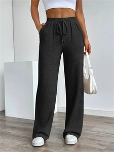 Detailed macro view of black high-waisted wide-leg trousers with textured waffle fabric