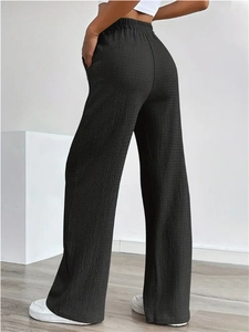 Detail of high-waist black wide-leg trousers featuring unique textured waffle fabric