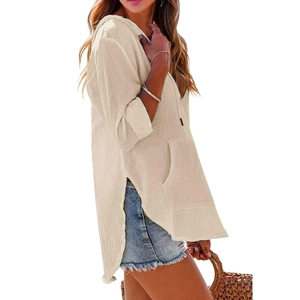 Dettaglio del top beige con cappuccio e scollo a V, tasca frontale e spacchi laterali