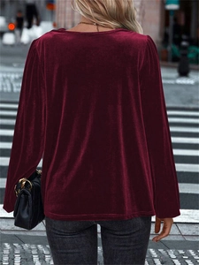 Outdoor street view showing the back profile of a burgundy velvet long-sleeve top