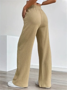 Detail view of khaki pleated texture fabric and elastic waist on wide-leg trousers