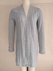 Detail of light blue cardigan featuring textured water-wave fabric and buttoned sleeves
