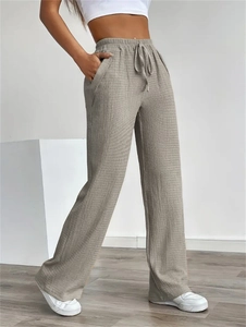 Detailed view of grey wide-leg trousers featuring drawstring elastic waist and crepe texture