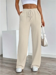 Detail of beige wide-leg pants showing waffle texture fabric and elastic drawstring waist
