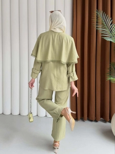 Vue arrière d'un ensemble deux pièces vert clair avec cape en dentelle et pantalon droit