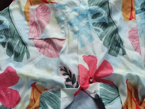 Detail of tropical floral print on a shirt with a patch pocket and woven fabric texture