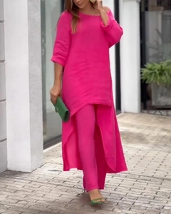 Detail of fuchsia two-piece set featuring long-sleeved asymmetrical top and matching pants