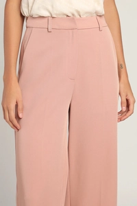 Detail of high-waist dusty pink wide-leg trousers with vertical drape and waist belt loops